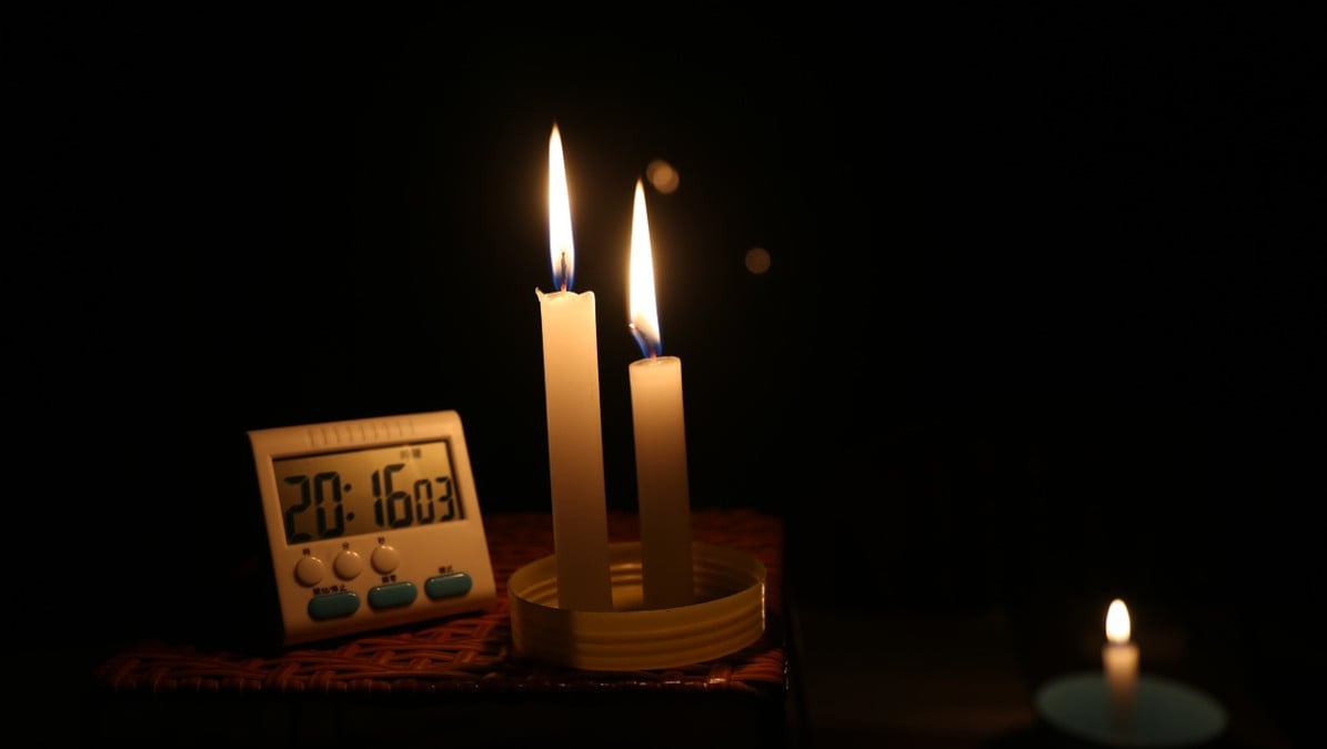 Candles provide the only light on a table with a small digital timer or clock