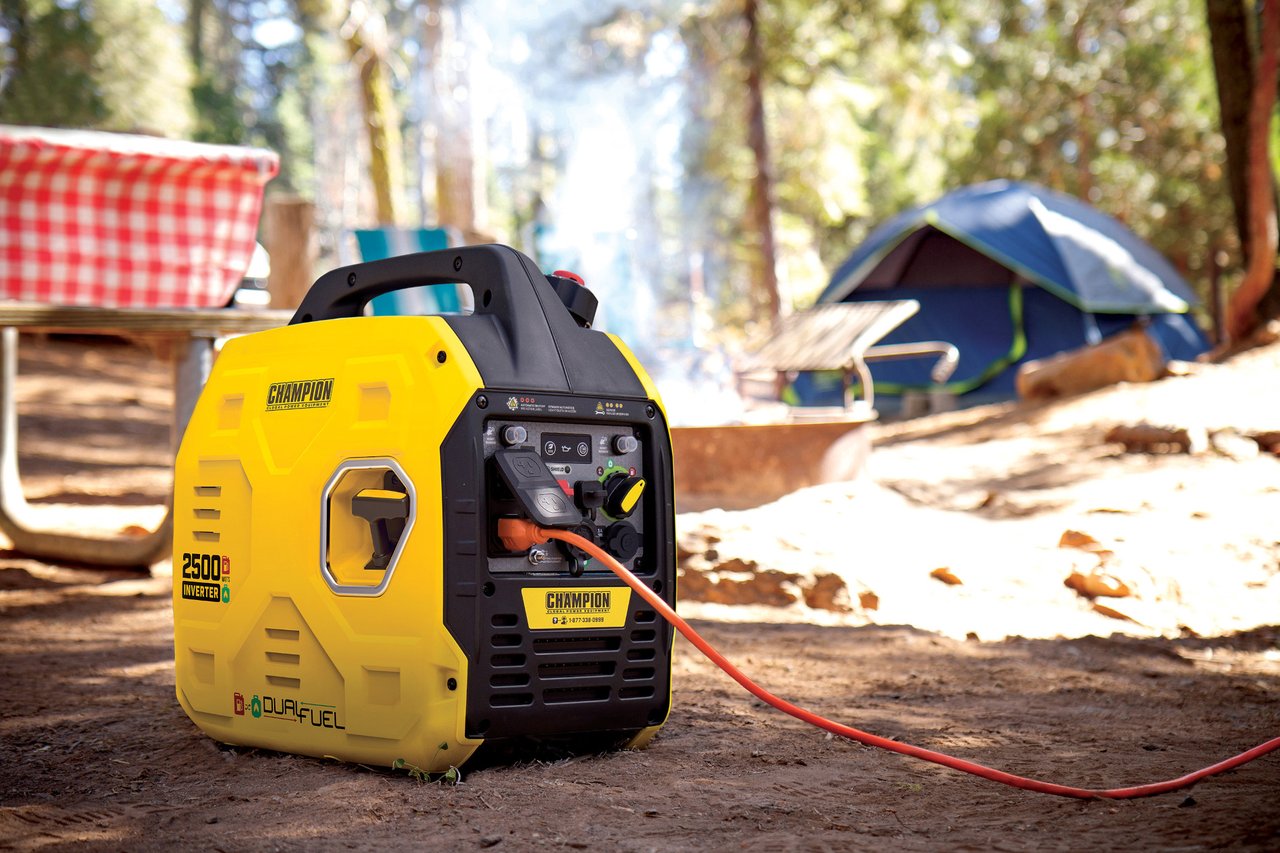 A Quiet Generator at a Wooded Campsite with an extension cord running to a tent in the background. Smoke rises from a fire pit with camp chairs around it. A checked table cloth covers a picnic table.