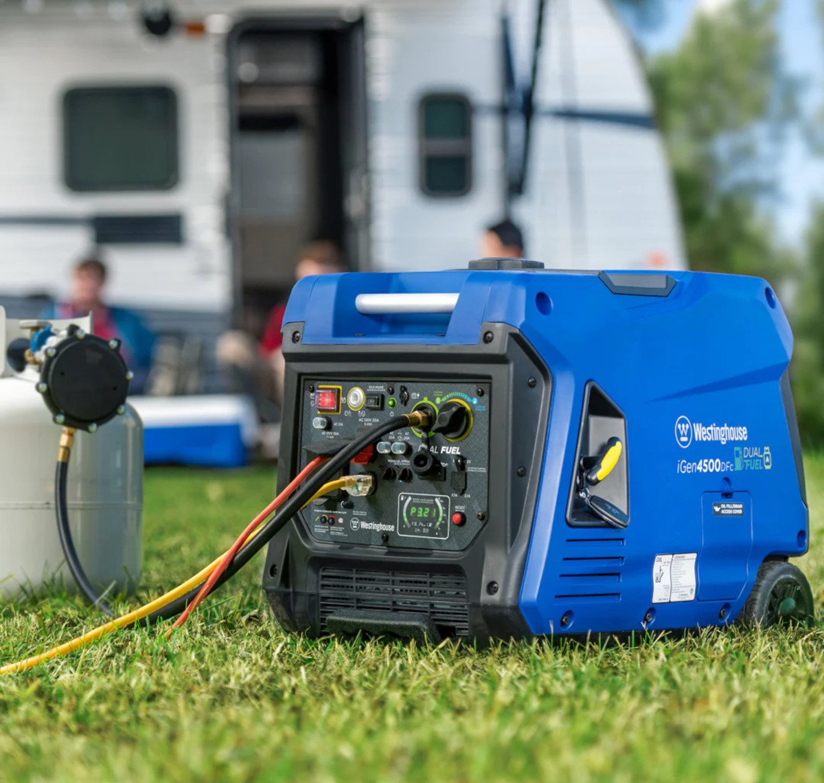 Portable RV Generator running on propane near a travel trailer. It's so quiet, the family can have a conversation while sitting on camp chairs under the RV canopy with snacks and drinks. The RV door is open. It's a beautiful summer day with green grass, blue skies, and trees in the background.