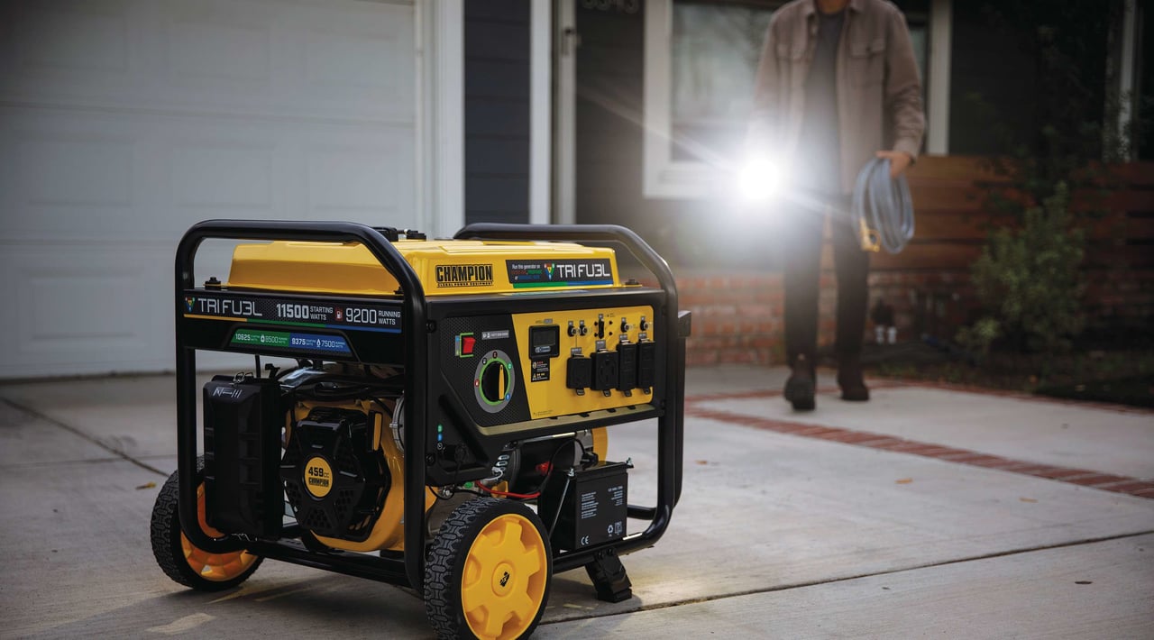A man brings a heavy duty generator cord to his portable generator on the driveway to connect it to the house during a power outage or blackout.