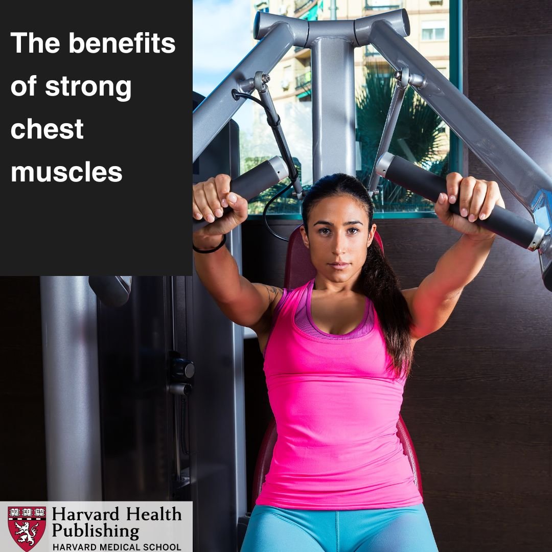 A woman in her thirties is sitting at a chest press machine, exercising her chest muscles.