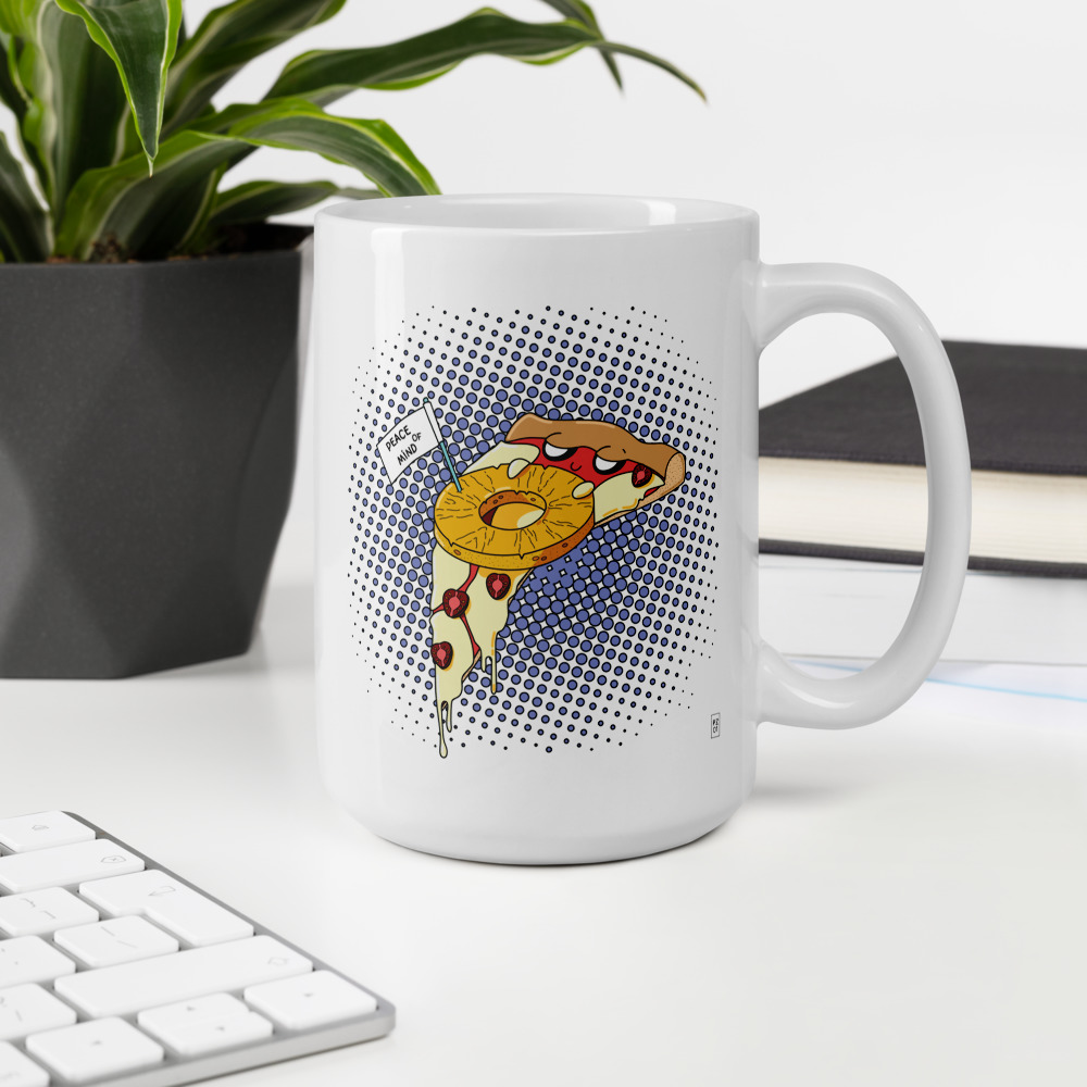 A mug with a print of pizza covered under a slice of pineapple.