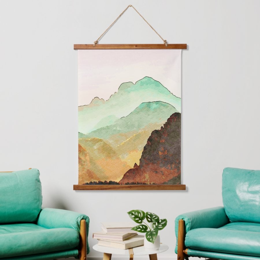 pretty watercolor mountain landscape scene in teals, gold and brown on a wall tapestry with wooden frame. 