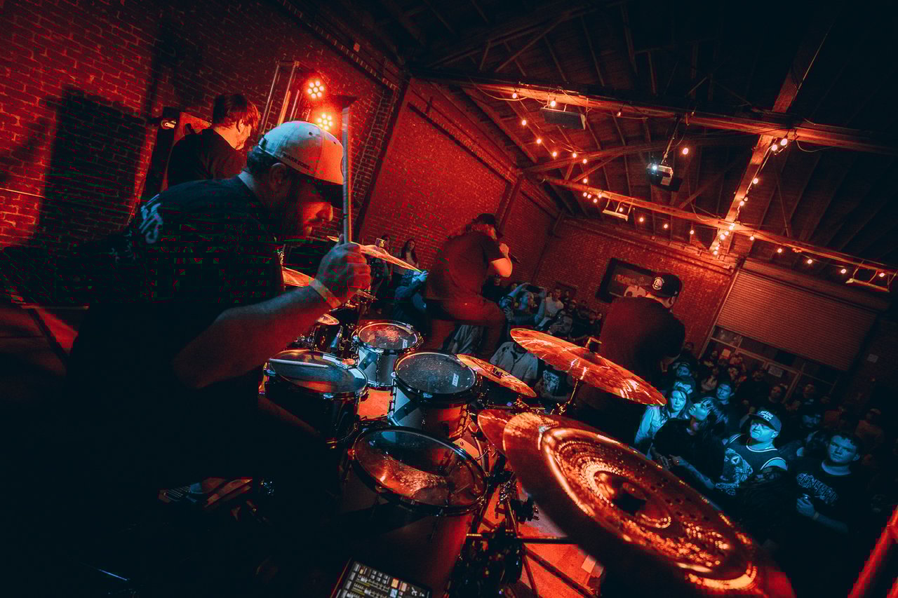 Three men on stage holding music equipment playing to a crowd