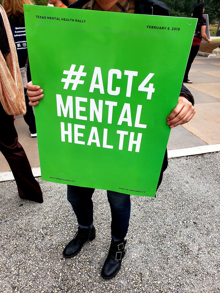 Picture of person holding 'Act 4 mental health' poster at a NAMI rally