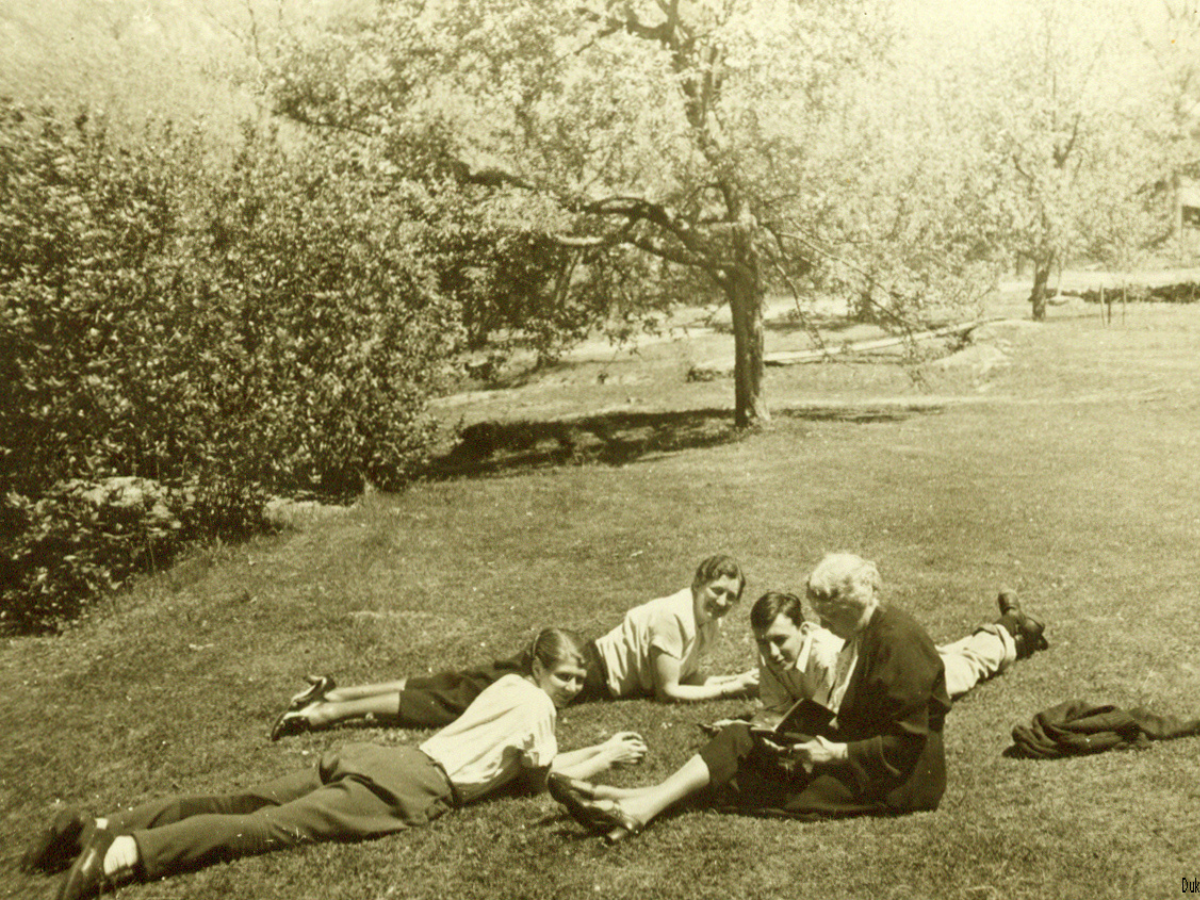 a vintage photo of people sitting in the grass