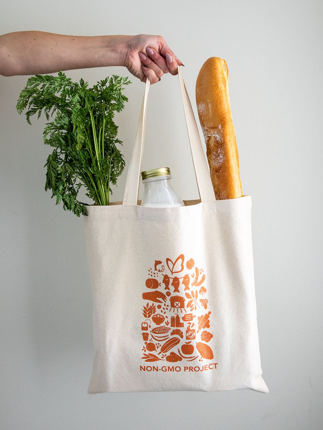 A Non-GMO Project canvas tote holding groceries