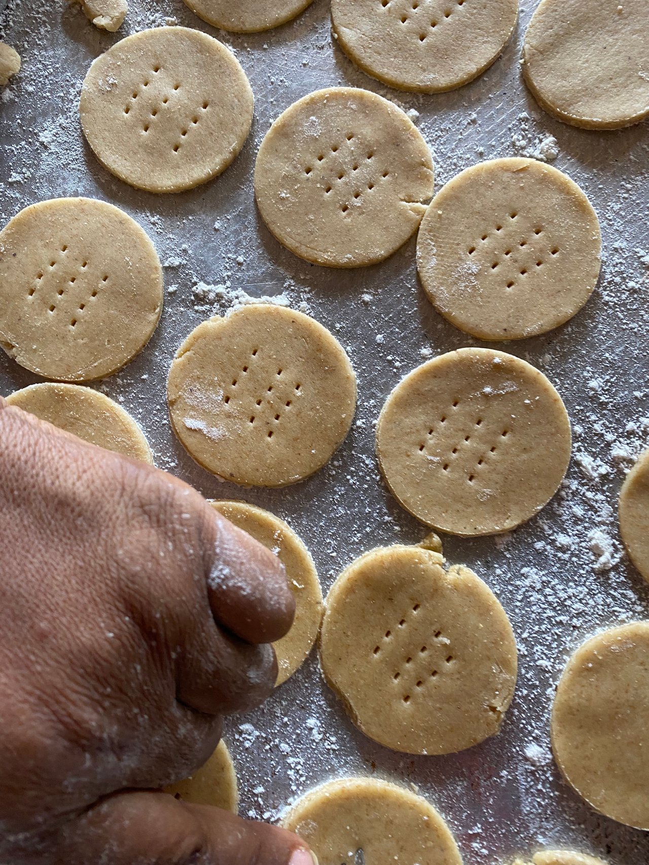 A close up of hands working digestive biscuit  dough on a floured surface