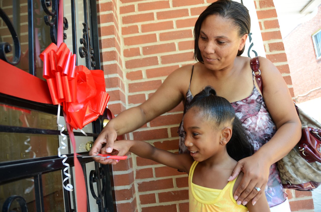 mother and daughter cutting ribbon for their new home