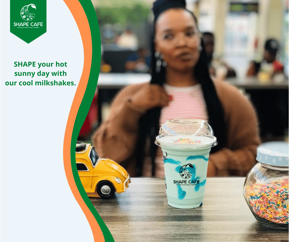 A smiling, young beautiful woman in a coffee shop with a milkshake