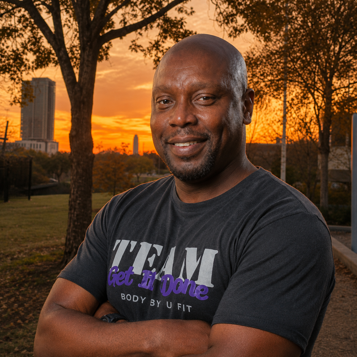Coach Phil, founder of Body By U Fit, smiling during an outdoor women's strength training session at Spotts Park in Central Houston, Texas.