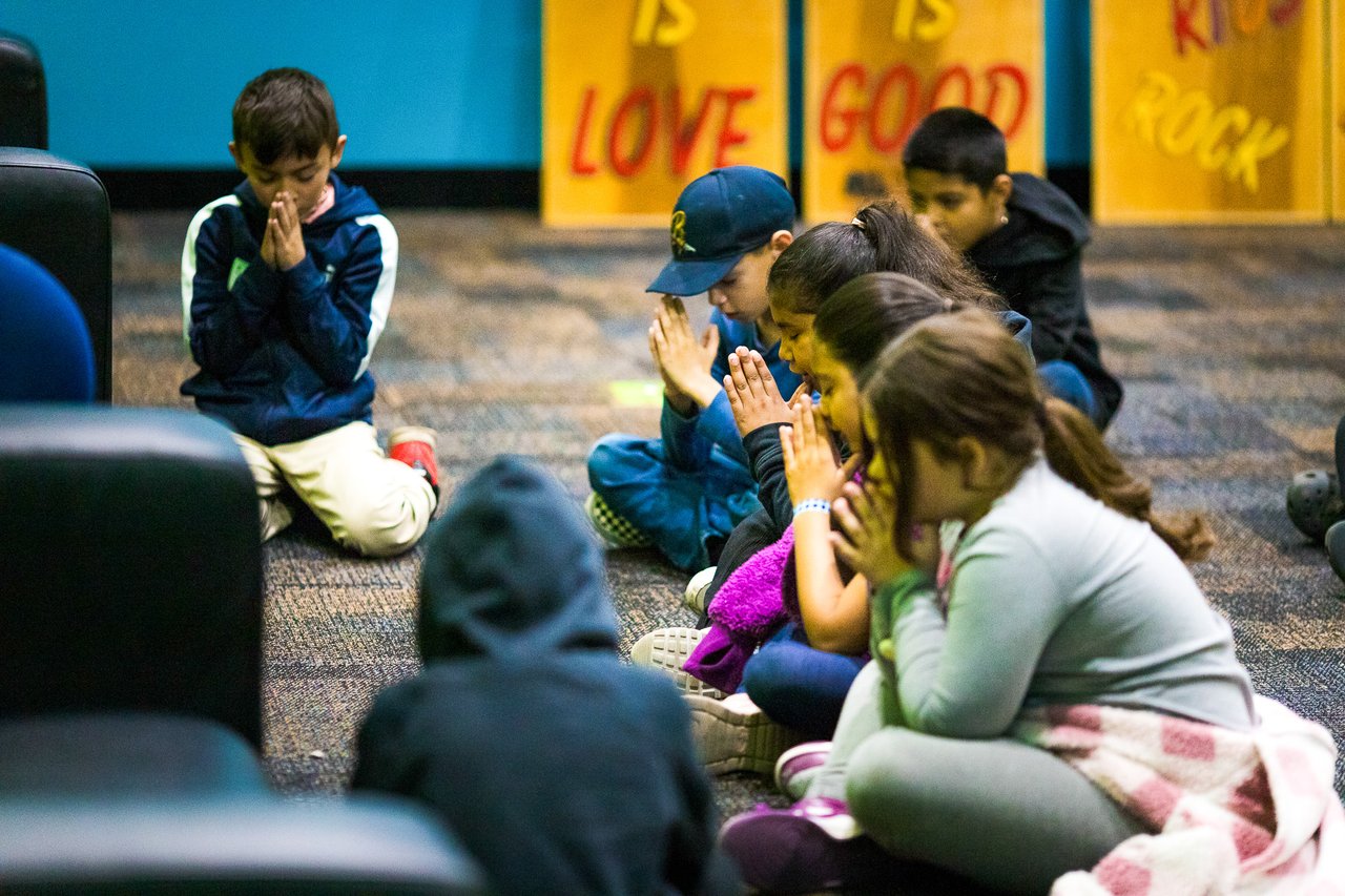 A group of kids praying in a circle