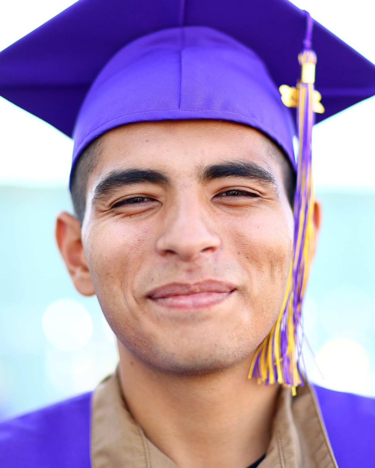 Photo of a male Sunburst Youth Academy high school graduate wearing purple cap and gown.