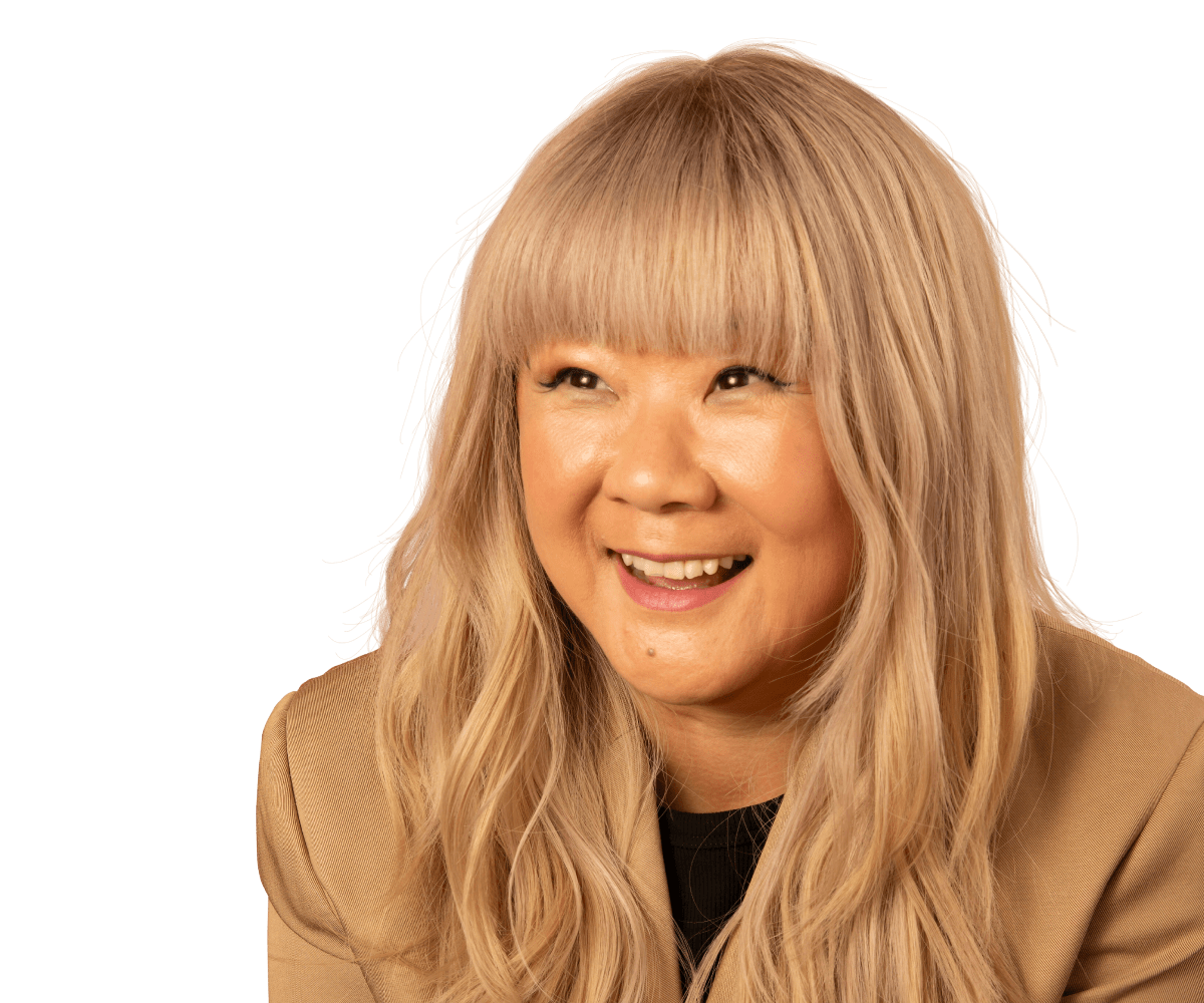 Comedienne Jenny Yang in a bright red jacket posing for a photo. 