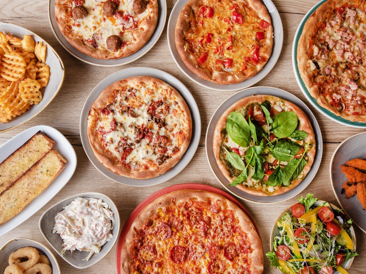 A selection of cooked pizzas and fries.