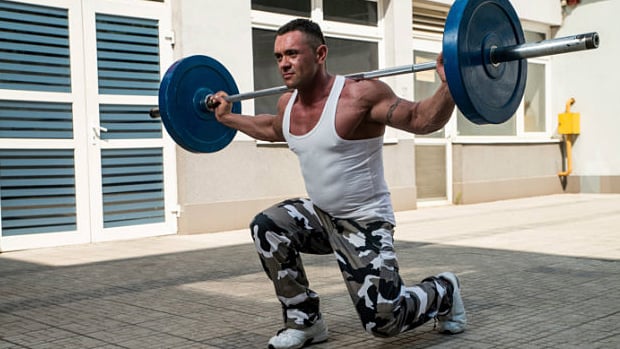 male doing a walking lunge with a 135 lb barbell