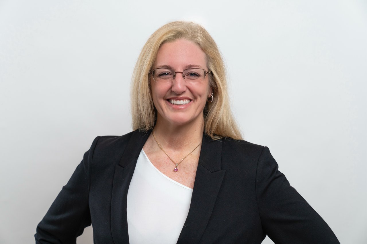 Pam Allen-LeBlanc in a black blazer, facing the camera with hands on hips.