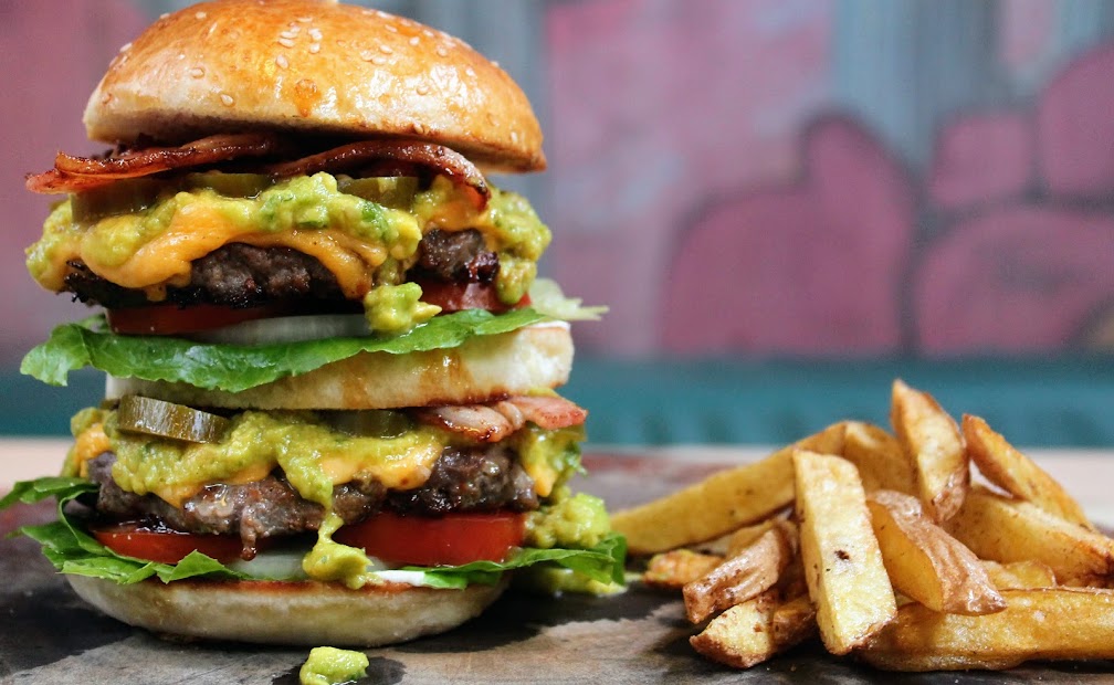 A double stacked and loaded burger with cheese, bacon, guacamole and jalapenos