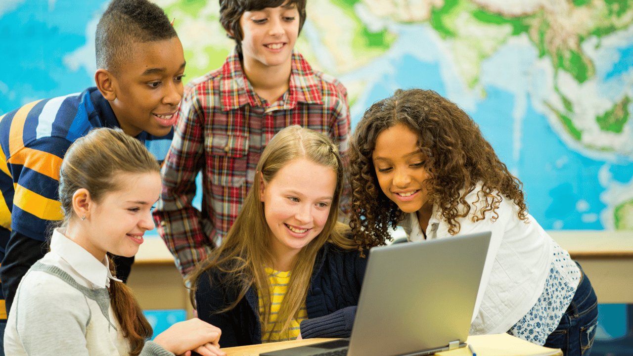 Young students gather around a laptop in a classroom