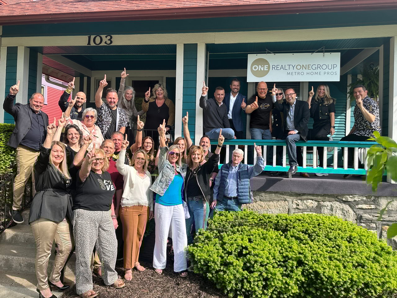 A large group of professional real estate agents in front of Realty ONE Group Metro Home Pros location
