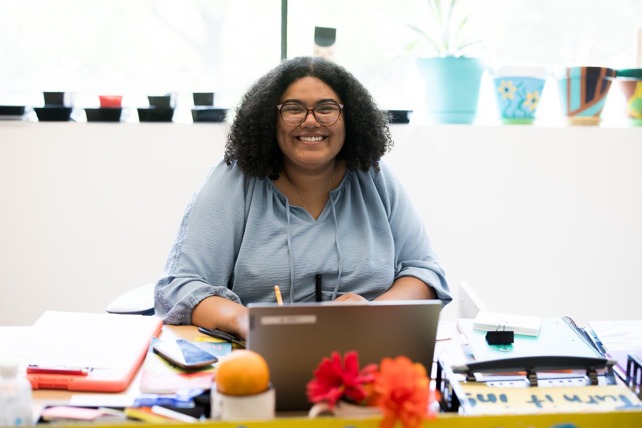 A person seated at a desk smiling at the camera.