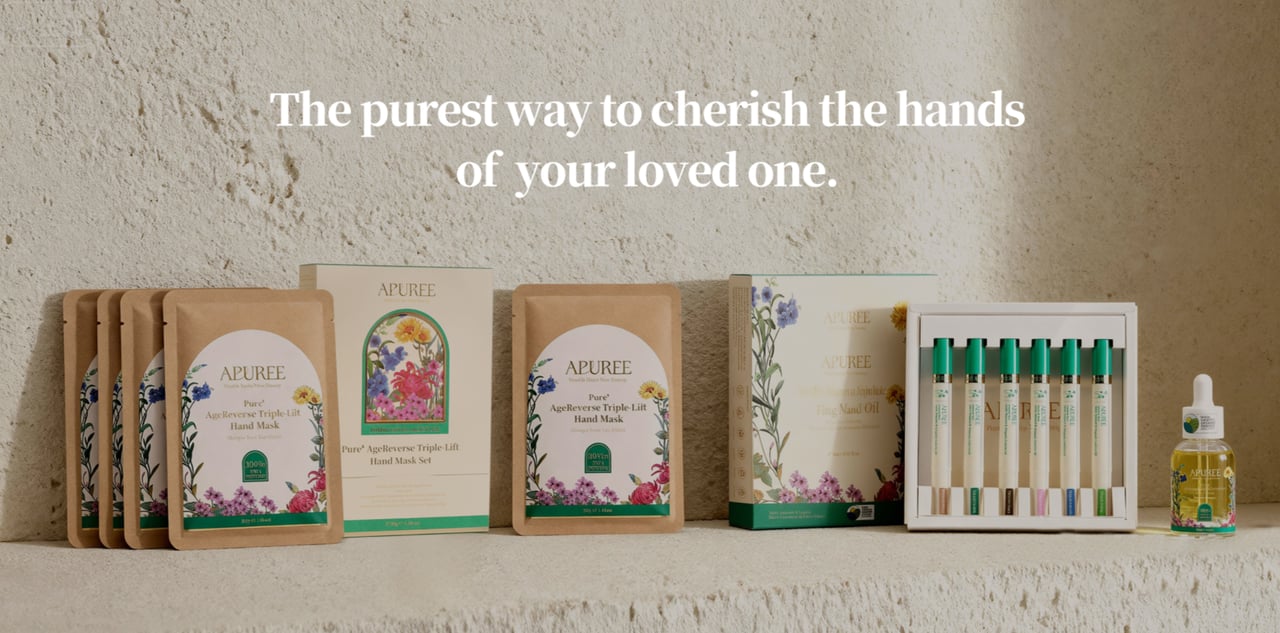 A person, unfocused, spritzing pink flowers in a vase with water from a yellow spray bottle