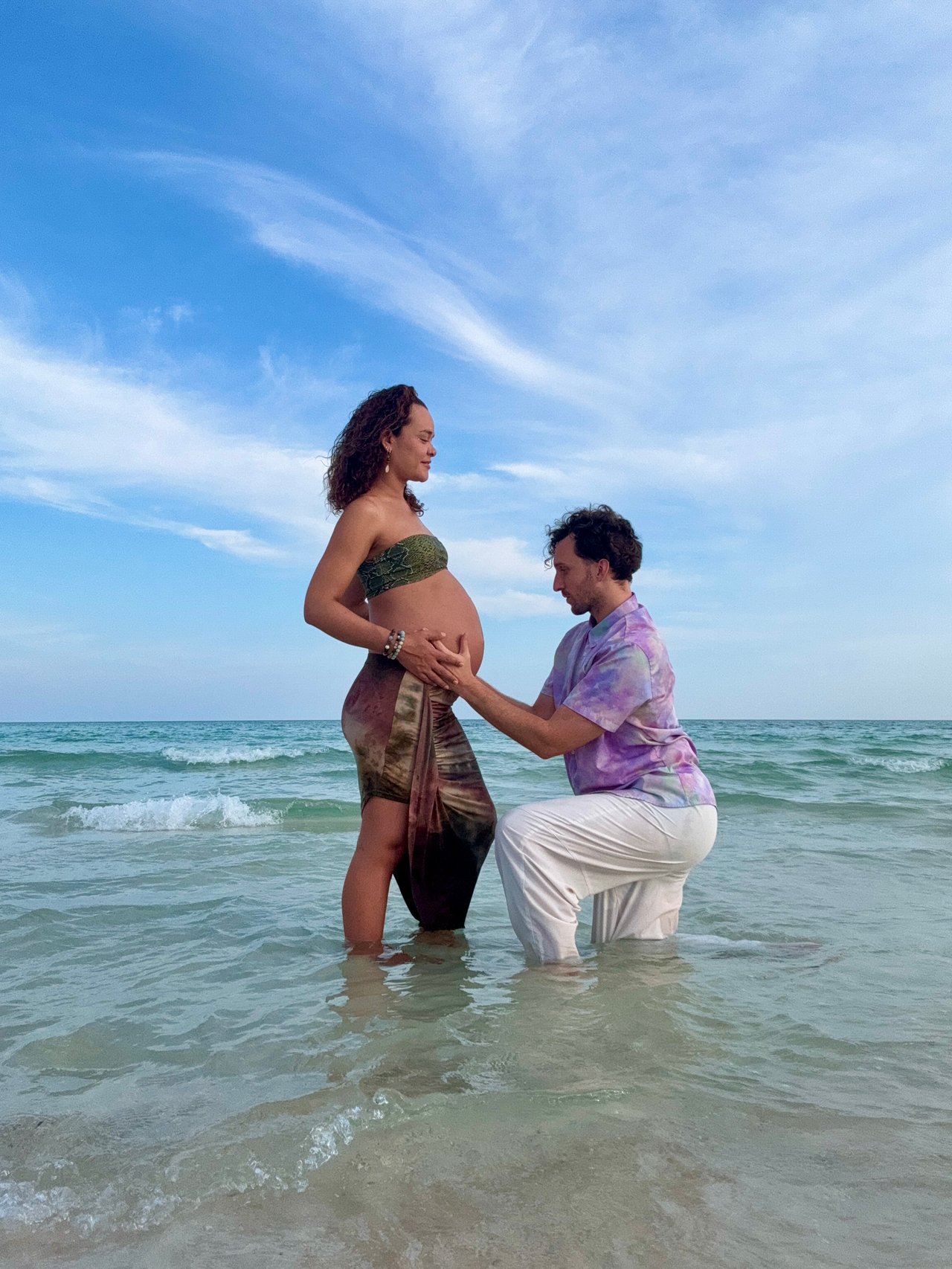 A person, unfocused, spritzing pink flowers in a vase with water from a yellow spray bottle
