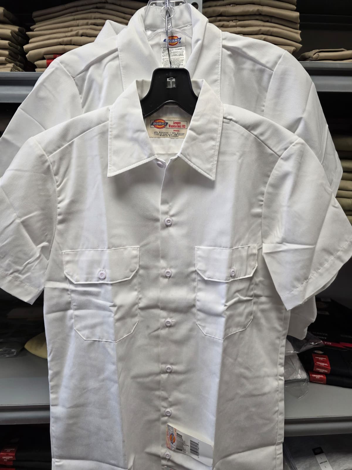A person, unfocused, spritzing pink flowers in a vase with water from a yellow spray bottle