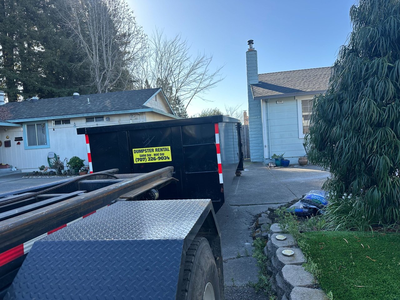 a feminine person with a full face of makeup and white leather choker and harness at a colourful rave. They're looking upwards and have a long nailed finger resting on their lips