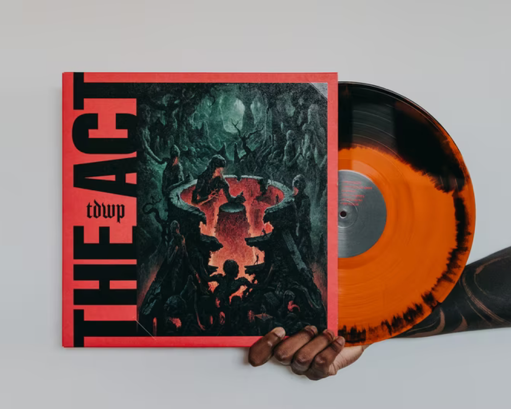 a person's cut off arm and hand holding an orange and black vinyl with the album cover showing on the left
