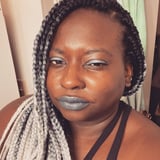 A dark-skinned Black woman with gray and white box braids.