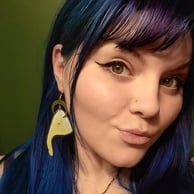 A young woman with blue hair and hazel eyes wearing luna moth wing earrings