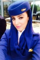 Alexoo pictured from the shoulders up under neon blue and organge lights. They wear a pair of black sunglasses