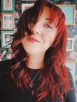 Siân, a young woman with long red hair smiling at the camera.