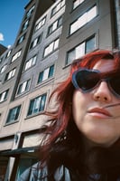 Siân, a woman with long red hair wearing heart shaped sunglasses.
