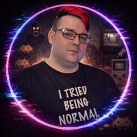 Alexoo pictured from the shoulders up under neon blue and organge lights. They wear a pair of black sunglasses