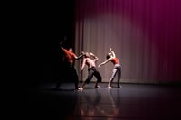 Three Dancers in a spotlight, arching backwards 