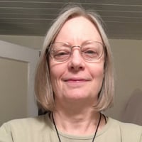 Headshot photo of a pale white woman with blondish, nearly straight shoulder-length hair and wire-rim glasses.