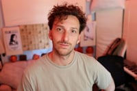 A man down on own knee in the ocean holding his wife's pregnant belly with a child growing within known as Malika.