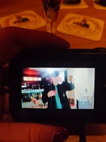Alexoo pictured from the shoulders up under neon blue and organge lights. They wear a pair of black sunglasses