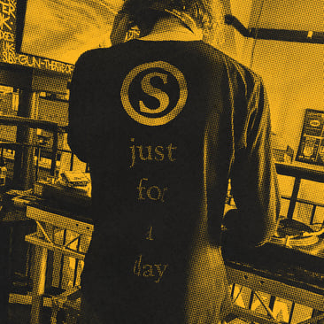 Black and yellow halftone image of DJ Yogi photographed from behind, wearing a hooded top printed with an "S" logo and the words "just for the day", set against a bar backdrop.