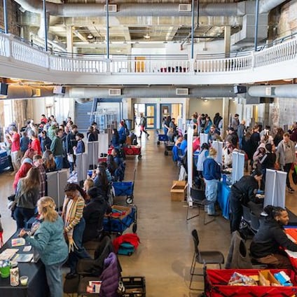 Crowds of community members gather at tables and booths during a Community Fair.